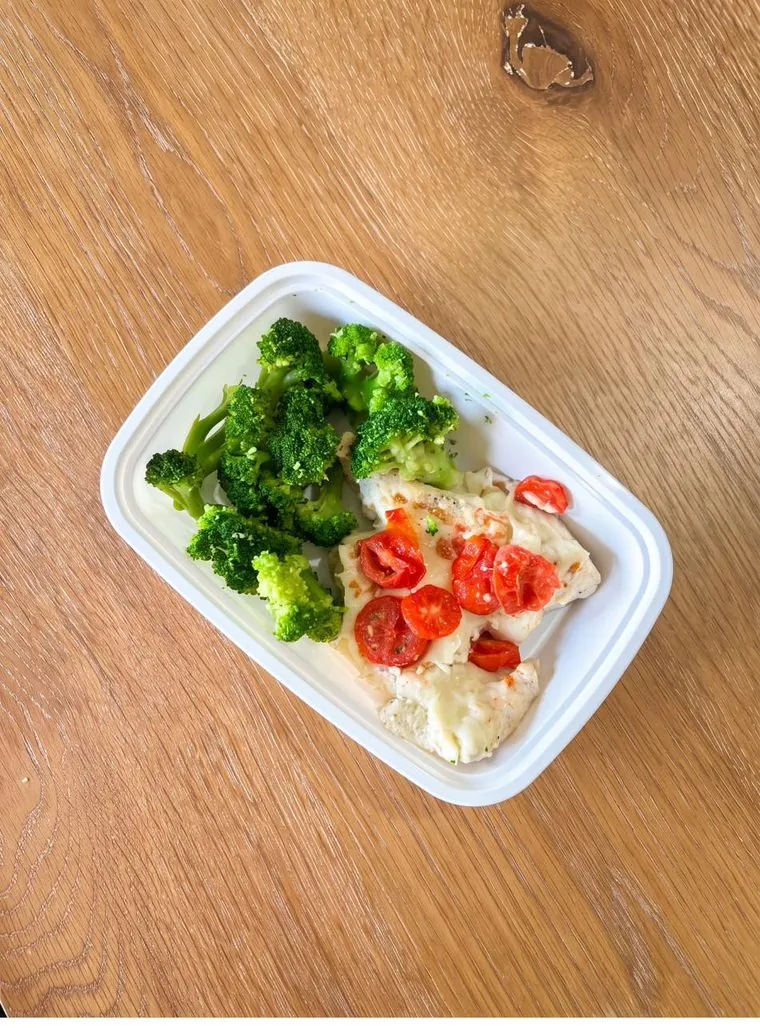 Pollo en salsa cremosa con tomates y brócoli sobre una mesa de madera